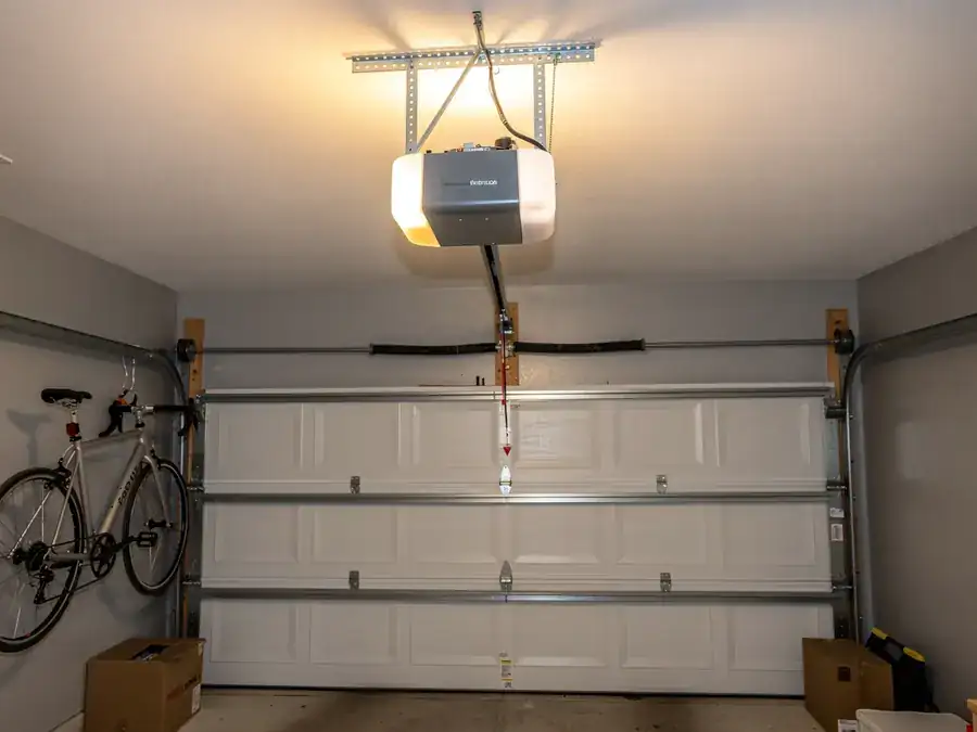 A garage door opener is mounted above a white garage door.